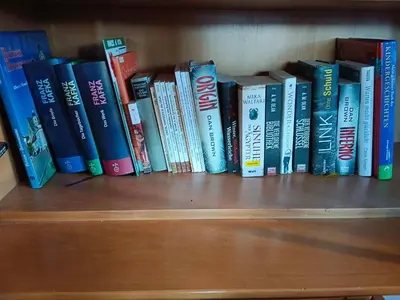 a row of books sitting on a book shelf at Plose Appartements in Bressanone