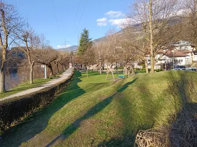 a park with green grass and trees and a sidewalk at Plose Appartements in Bressanone