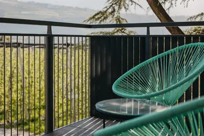 a green chair on a balcony with a fence at Apart Suites Gravbach in Lagundo