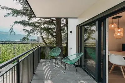 a house with a balcony with chairs and a tree at Apart Suites Gravbach in Lagundo