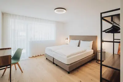 a bedroom with a bed and a desk and a chair at Apart Suites Gravbach in Lagundo