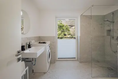 a bathroom with a sink and a washing machine at Apart Suites Gravbach in Lagundo