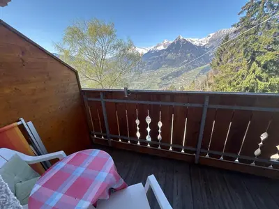 a balcony with a table and a chair and mountains at Hotel Rastlhof in Schenna