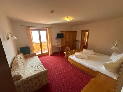 a bedroom with a bed and a couch and a window at Hotel Rastlhof in Schenna