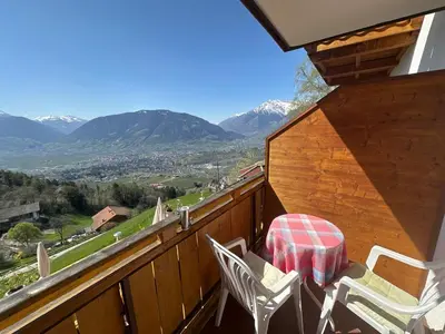 a balcony with a table and chairs and mountains at Hotel Rastlhof in Schenna