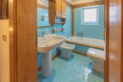 a blue tiled bathroom with a sink and a toilet at Casa Cristallino, in centro con balcone panoramico in Cortina dʼAmpezzo