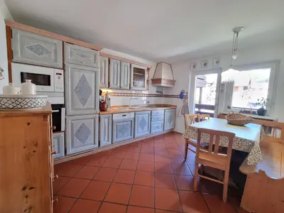 a kitchen with white cabinets and a table with chairs at Anto in Campitello di Fassa