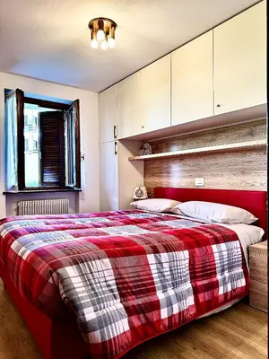 a bedroom with a bed with a red and white blanket at Il Moro di Cavalese in Castello di Fiemme
