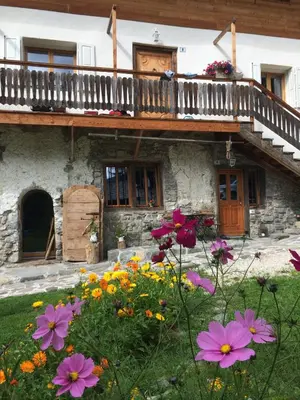 an old house with flowers in front of it at la fusinela in Selva di Cadore