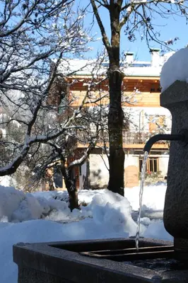 a water fountain with snow in front of a house at la fusinela in Selva di Cadore
