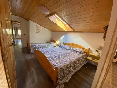 two beds in a room with a wooden ceiling at Appartamento Franca in Pera