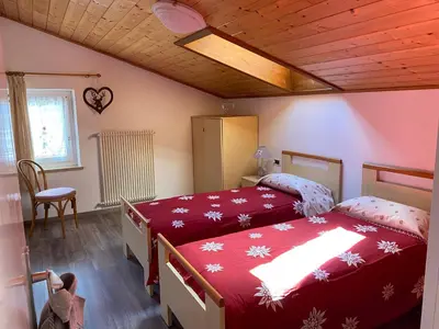 a bedroom with two beds and a table and a chair at Appartamento Franca in Pera