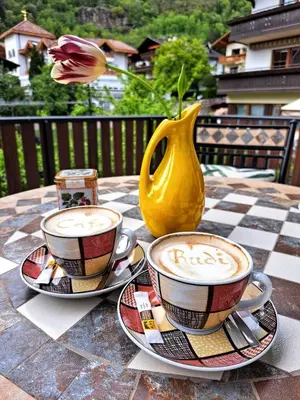two cups of coffee on a table with a vase at Cafe Rudi Living Apartements in Parcines