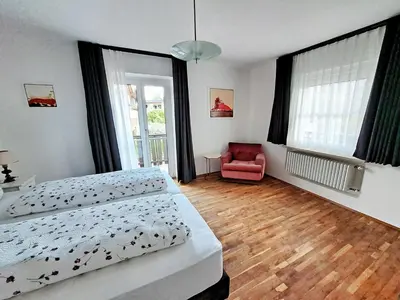 a bedroom with two beds and a red chair at Cafe Rudi Living Apartements in Parcines