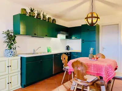 a kitchen with green cabinets and a table with chairs at Apartment in South Tyrol with a beautiful panoramic view in Verano