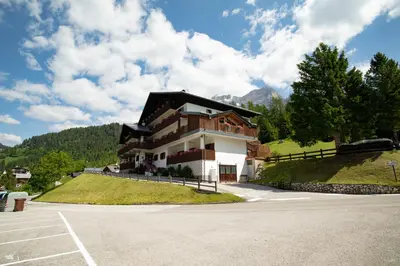 a large house on a hill with a parking lot at Residence Panorama in Val di Zoldo