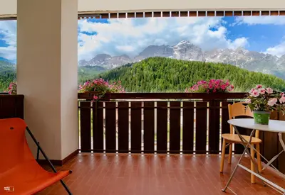 a room with a balcony with a view of mountains at Residence Panorama in Val di Zoldo