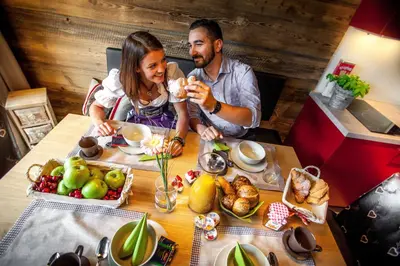 a man and a woman sitting at a table with food at Chalet Stefan - Apartments in La Villa