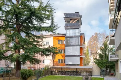 an apartment building with a tower in a city at Gardar in Bolzano