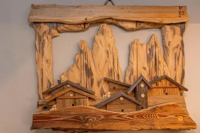 a wooden picture of a house on a wall at Casa Te Volto in Moena