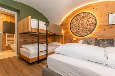 a bedroom with two bunk beds and a bathroom at Casa Te Volto in Moena