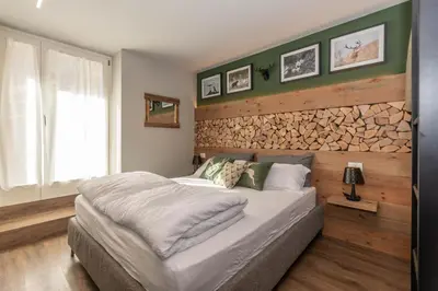a bedroom with a large bed and a wooden wall at Casa Te Volto in Moena