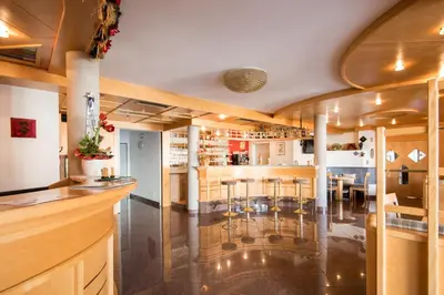 a bar in a restaurant with stools in a room at Hotel Föhrenhof in Naz-Sciaves