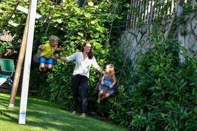 a woman and two children on a swing at Hotel Föhrenhof in Naz-Sciaves