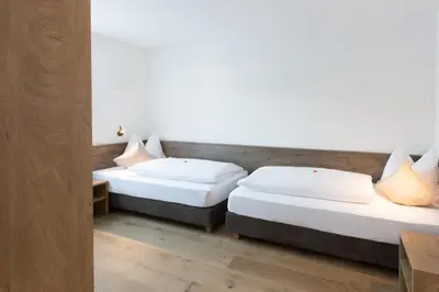 two beds in a room with white walls and wooden floors at Hotel Föhrenhof in Naz-Sciaves