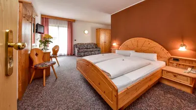 a bedroom with a large bed and a chair at Hotel Föhrenhof in Naz-Sciaves
