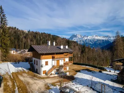 a small house in the snow with mountains in the background at Ciasa al Sol in Falcade