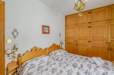 a bedroom with a bed and a wooden cabinet at Ca' dello Scoiattolo in Cortina dʼAmpezzo