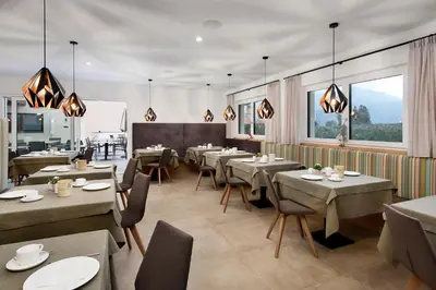 a dining room with tables and chairs and windows at Pension Pichler in Tirolo