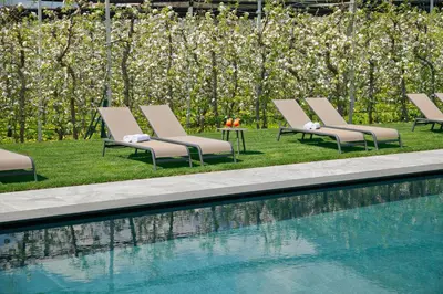 a row of lounge chairs next to a swimming pool at Pension Pichler in Tirolo