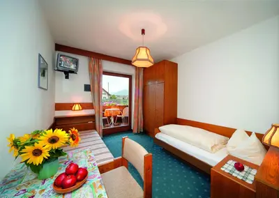 a hotel room with a bed and a table with flowers at Pension Pichler in Tirolo