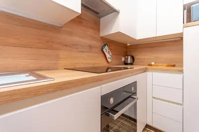 a kitchen with white cabinets and wooden walls at Appartamento Cordevole in Rocca Pietore