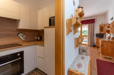 a kitchen with white cabinets and a table in it at Appartamento Cordevole in Rocca Pietore