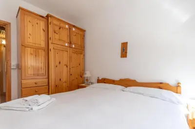 a bedroom with a white bed and wooden cabinets at Appartamento Cordevole in Rocca Pietore