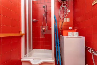 a red bathroom with a shower with a red tiled wall at Appartamento Cordevole in Rocca Pietore