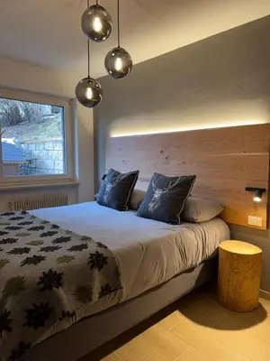 a bedroom with a large bed with a wooden headboard at Ciasa Saslonch Apartment in Moena