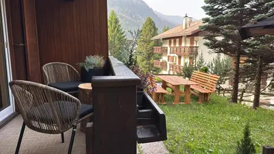 a patio with chairs and a table and a bench at Ciasa Saslonch Apartment in Moena