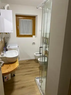 a bathroom with a toilet and a glass shower at Appartamento Miramonti in Mas