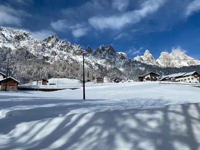 a snow covered village with mountains in the background at Appartamento Miramonti in Mas
