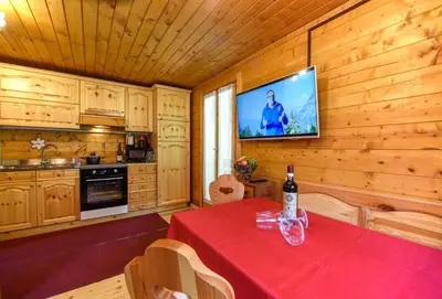a dining room with a table and a television in a cabin at Fienile Rustico Alleghe Tabià in Alleghe
