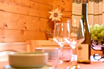 a table with a bottle of wine and a glass at Fienile Rustico Alleghe Tabià in Alleghe