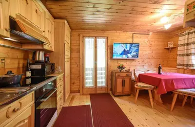 a kitchen with a table in a wooden cabin at Fienile Rustico Alleghe Tabià in Alleghe