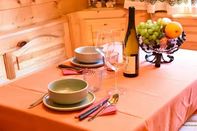a table with plates and glasses and a bottle of wine at Fienile Rustico Alleghe Tabià in Alleghe