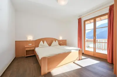a bedroom with a bed and a large window at Ferienwohnungen Fuchsleitenhof am See in Caldaro