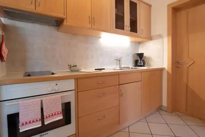 a kitchen with wooden cabinets and a white stove top oven at Ferienwohnungen Fuchsleitenhof am See in Caldaro
