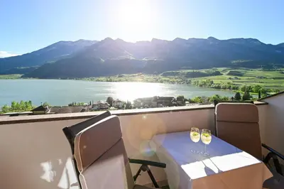 a table and chairs on a balcony with a view of a lake at Ferienwohnungen Fuchsleitenhof am See in Caldaro
